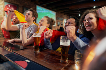 Group of friends cheering to soccer match in the pub