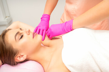 Fototapeta na wymiar Waxing. Depilation under the armpits of the young woman lying with closed eyes in the spa salon