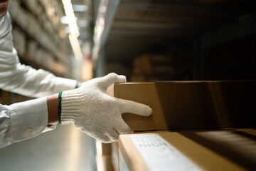 Close-up of a worker's hand checking goods and supplies on a shelf in a warehouse. Asian engineer inspects goods and materials on shelves with goods background in warehouse. Logistics and export.
