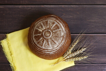 Freshly baked bread and ears of rye lie on a wooden board. Harvest. Top view. Selective focus