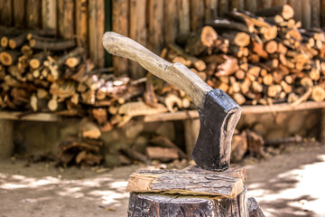 Firewood is split and stacked for the winter heating season. Background of stacked firewood, chopped wood for the stove. Ax for cutting wood.