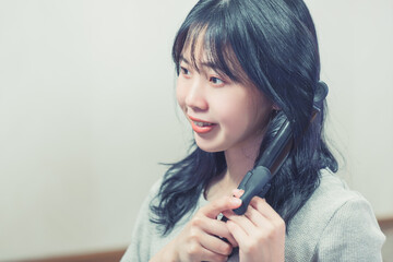 Obraz premium ヘアーアイロンで髪の毛を巻く女性 hair iron