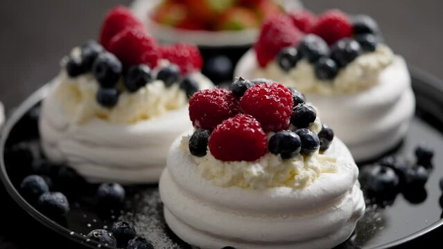Delicious mini pavlova meringue desserts served with frozen frosty berries