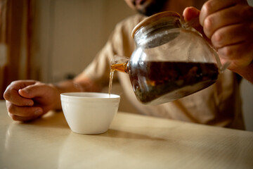 a man at home in the kitchen pours tea into a cup