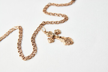Gold chain with golden cross pendant on white background