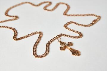 Gold chain with golden cross pendant on white background