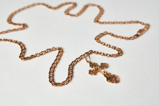 Gold chain with golden cross pendant on white background
