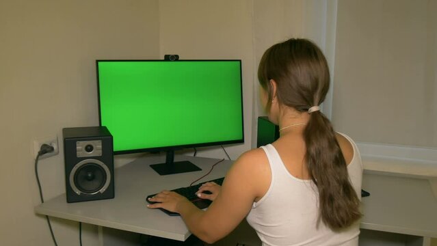 Girl is typing text on the keyboard. Chromakey on computer screen. Video with a chroma key on the screen to insert any video or image.