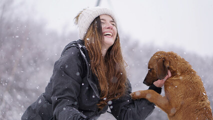 Young woman playing with a dog in the snow.