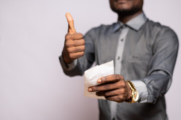 african man stretching an envelope forward, does thumbs up