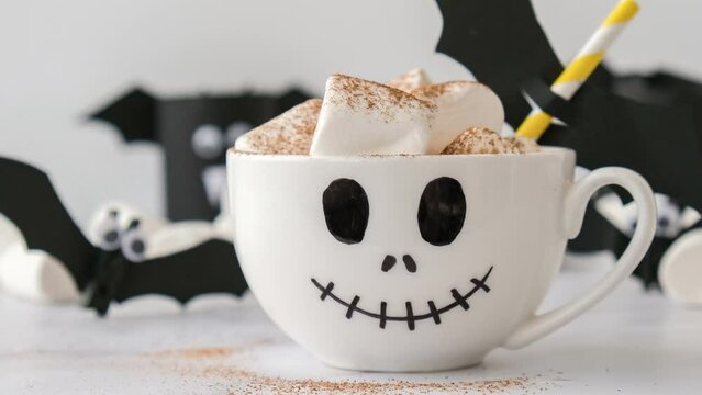 4k zoom in out Painted white cup scary jacks face with marshmallows Hot chocolate cacao drink DIY for kids. Halloween home activities Holiday art children craft Handmade decorations home Idea for art