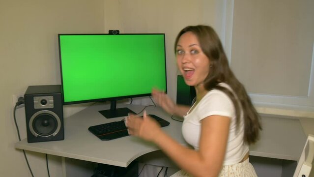 Girl is very happy with what is shown on the computer screen. Chromakey on computer screen. Video with a chroma key on the screen to insert any video or image.