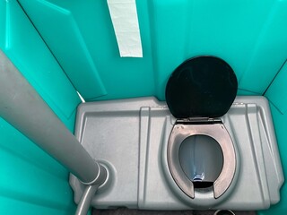 Well maintained plastic public urinal with grey bowl and toilet paper roll hanger. Image of a public toilet cabin.