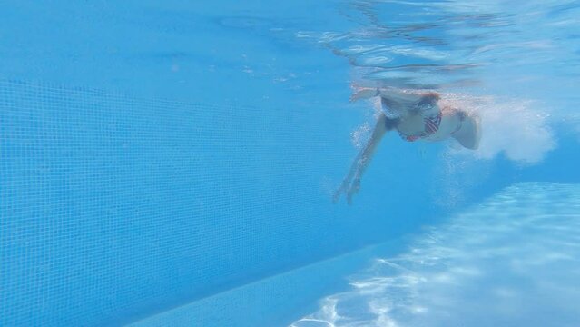 underwater image of a beautiful athletic young woman swimming the crawl and doing a U-turn