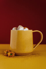 Still life of a yellow mug of hot cocoa with marshmallows.