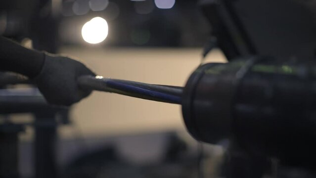 A Male Production Worker Wearing Gloves Puts A Bundle Of Cables Into The Cable Braiding Machine. Close-up. Putting Insulation On The Cable. Production Process. Cable Factory. 4K