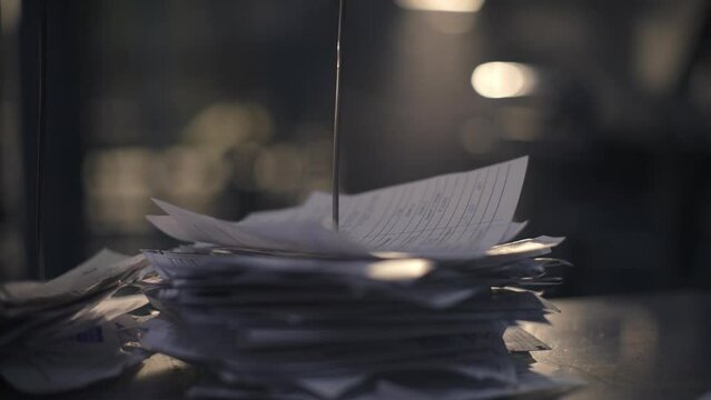 Paper sheets on a steel spoke. A man's hand attaches completed tasks of the workshop to the spoke. Completed checks. Close-up. List of tasks for the factory. 4K