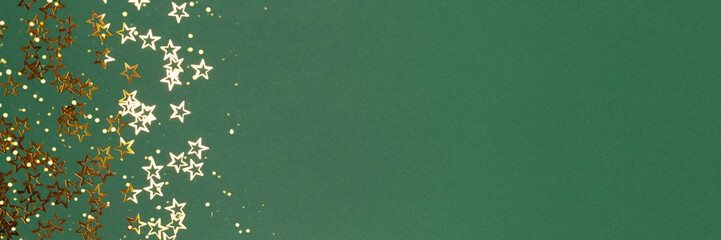 Banner with metallic gold colored stars confetti on a green background with place for text.