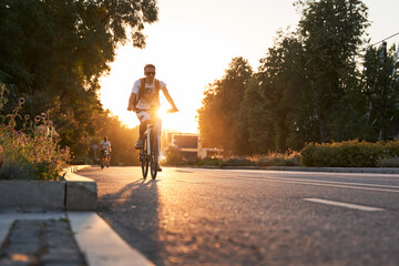 Man is riding on bicycle on the street on the sunset.