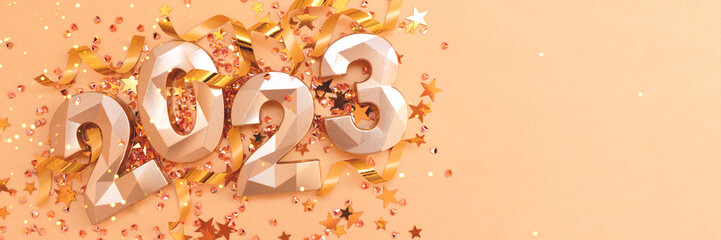 Banner with 2023 gold colored numbers, ribbons and stars confetti. Monochrome New Year's...