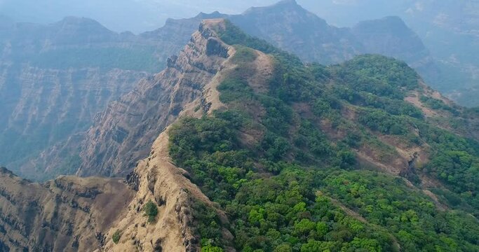 Aerial shot of ridge with steep rocky cliffs and tropical vegetation