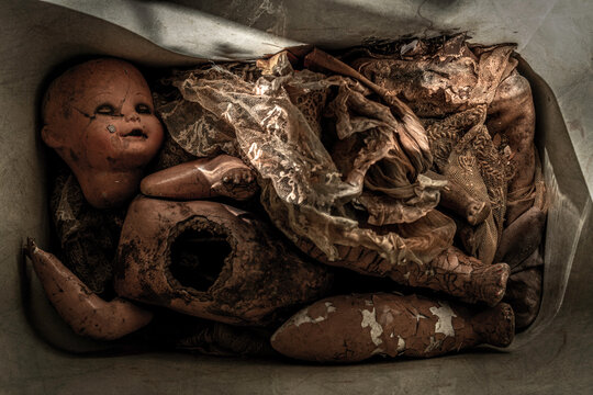 Dirty and damaged doll covered by rags inside a box. Scary Baby Doll. Disturbing horror movie concept for dark mood