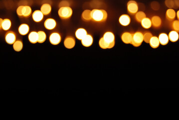 De focused lamps yellow lights in the dark, a line of blurred lamps lights in the dark