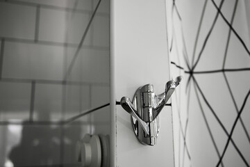 Wall stainless steel chromed triple hook on the white tile wall in the bathroom. Modern detail of interior design. Shiny accessory. Towels holder. Copy space