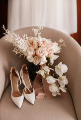 The bride's wedding bouquet of roses and orchids and the bride's shoes