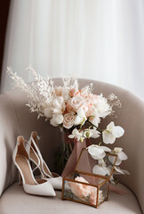 The bride's wedding bouquet of roses and orchids and the shoes and wedding rings