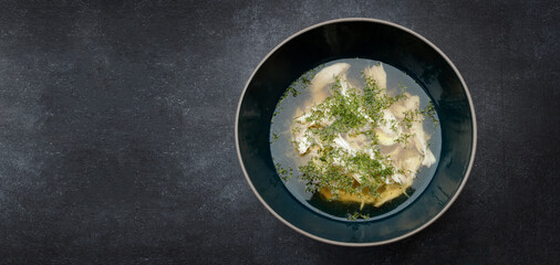Chicken broth with dill, consomme, on a dark background