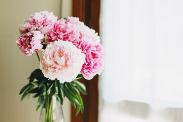 Beautiful bouquet of pink pastel peony flowers near the window.