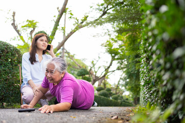 Fototapeta na wymiar Asian senior woman fell down on lying floor because faint and limb weakness and pain from accident and woman came to help support and call emergency. Concept of old elderly insurance and health care