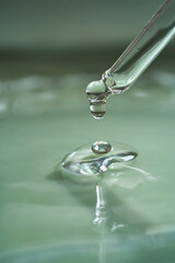 Dropper with serum or cosmetic oil on a green background.