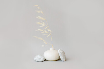 Still life with dry spikelets of wild oats and stones. Grey background.