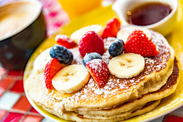 Belgian pancakes served with fruits and maple syrup
