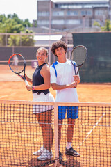Outdoor on the clay court smiling cute young man and woman posing in front of the camera and...