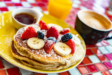 Belgian pancakes served with fruits and maple syrup