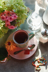 A cup of tea with bouquet of phlox and gortensia flowers, morning tea concept.
