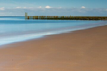 A sandy beach at the North sea in the Netherlands seen from the beach in Zoutelande in Zeeland with the typical wooden breakers for the waves during high water