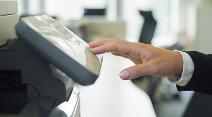 a woman uses a printer in the office. close-up of a woman's hand using buttons on a scanner printer