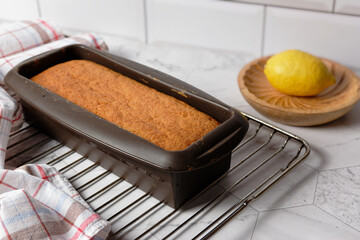 Homemade lemon cake in a silicone box mold, placed on an oven rack to cool