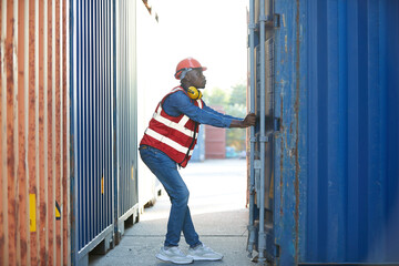 African factory worker or foreman opening the container door in warehouse storage