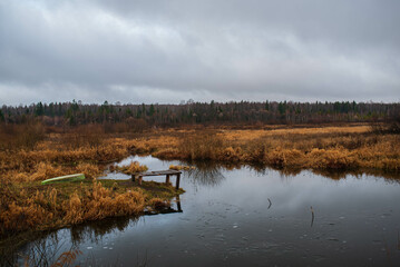 Old rustic wooden jetty on a tranquil lake with wild grasses on the bank and reflections on the water