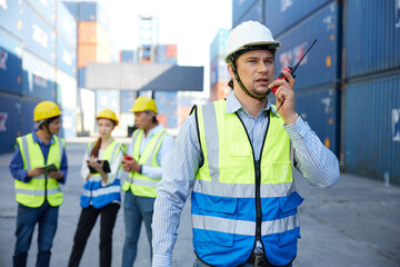 factory worker or engineer using walkie talkie and talking about work in containers warehouse storage
