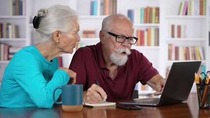 Elderly couple home finances, reviewing their bank money accounts using laptop stressful emotion at home