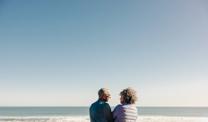 Happy elderly couple smiling at each other at the beach