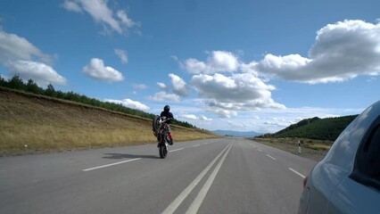 Biker shows off a stunt ride on the back wheel of a motorcycle on the empty mountain road