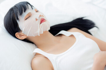 Beautiful young asian woman with sheet facial mask and sleep on bed at bedroom, beauty girl...