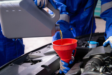 Closeup hands of mechanic man pouring motor oil in engine car in the garage, automobile change...